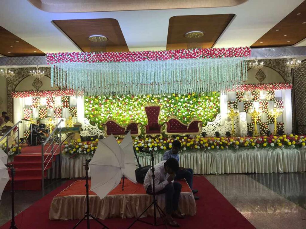 Wedding reception stage with floral backdrop and crystal drapes