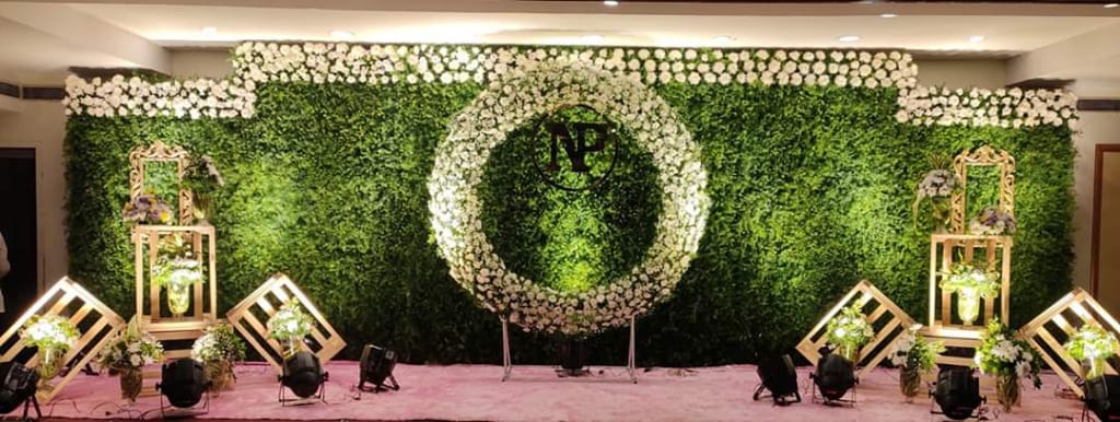 Engagement stage with green leaf wall and white rose ring