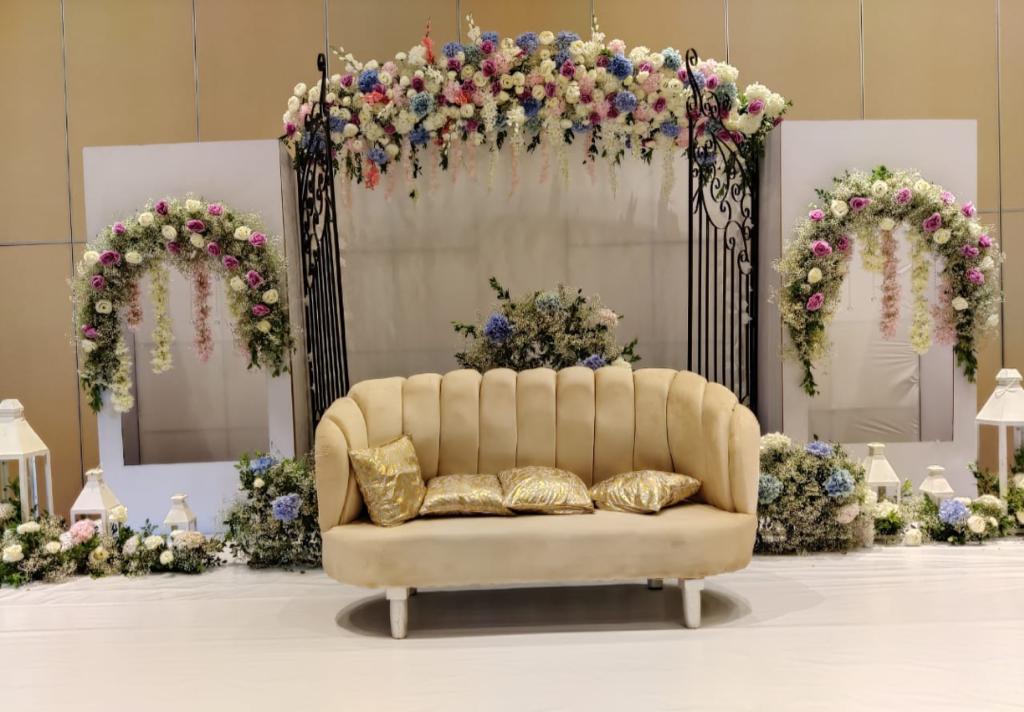 Reception sofa setup with pastel florals and iron gate backdrop