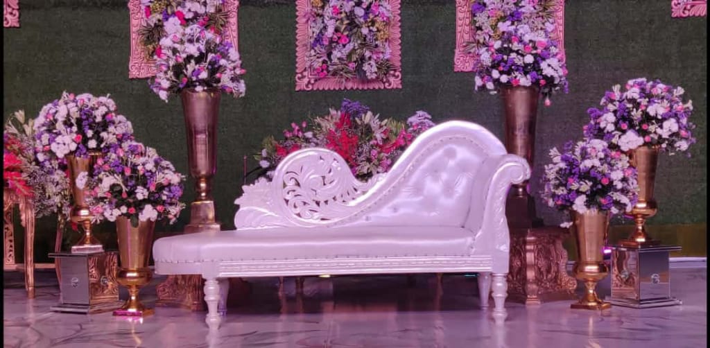 Reception stage with carved chaise and purple floral vases